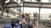 Los desplazados venezolanos María Fernanda Artigas, 22 (centro, camiseta verde) abraza a su pareja, Endry Cordero Ávila, de 22 años, mientras su hija Jerley, de 17 meses, disfruta de una bebida fría frente a la terminal de autobuses de Cali, Colombia, el 1 de diciembre de 2022. 