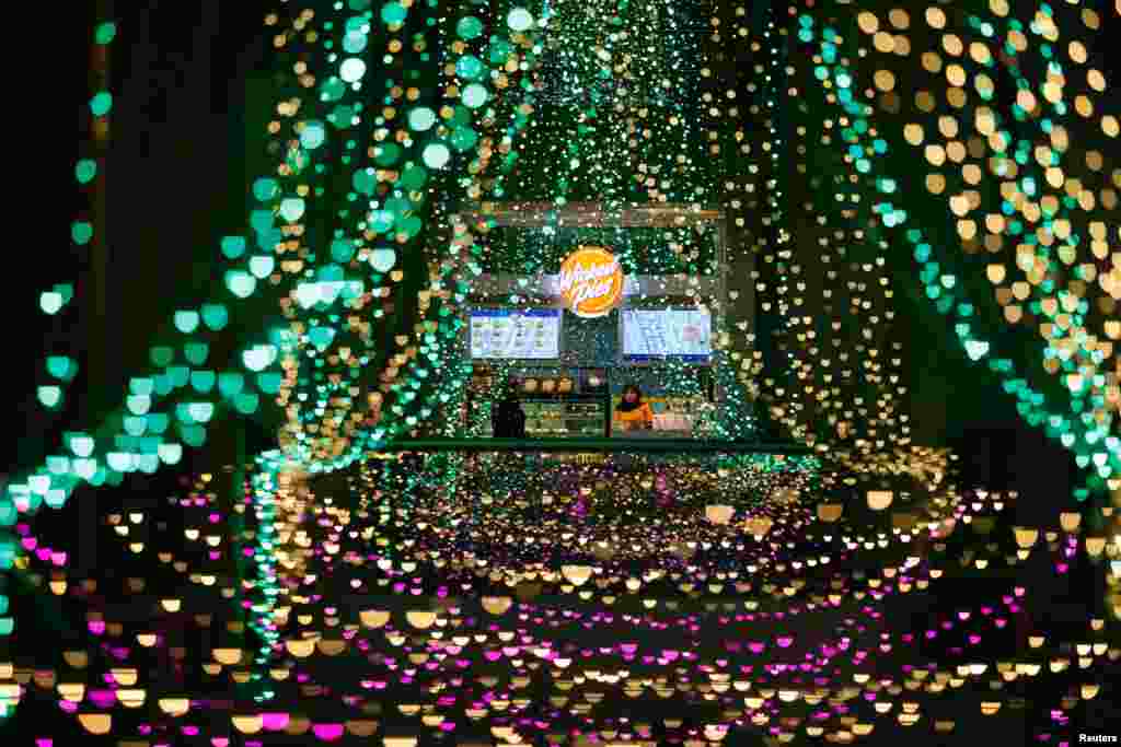 A shopkeeper waits for customers at a stall inside a shopping mall with light decorations installed ahead of the Ramadan festive in Jakarta, Indonesia, March 20, 2023.