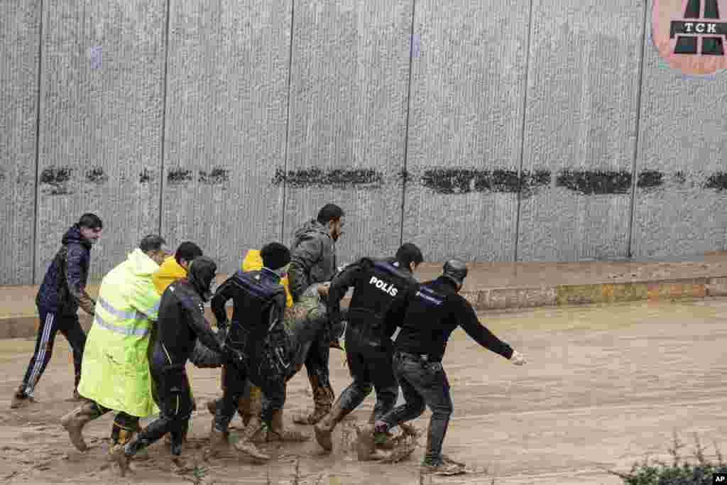 Police and rescue team members carry the body of a person found during flooding after heavy rains, in Sanliurfa, Turkey.