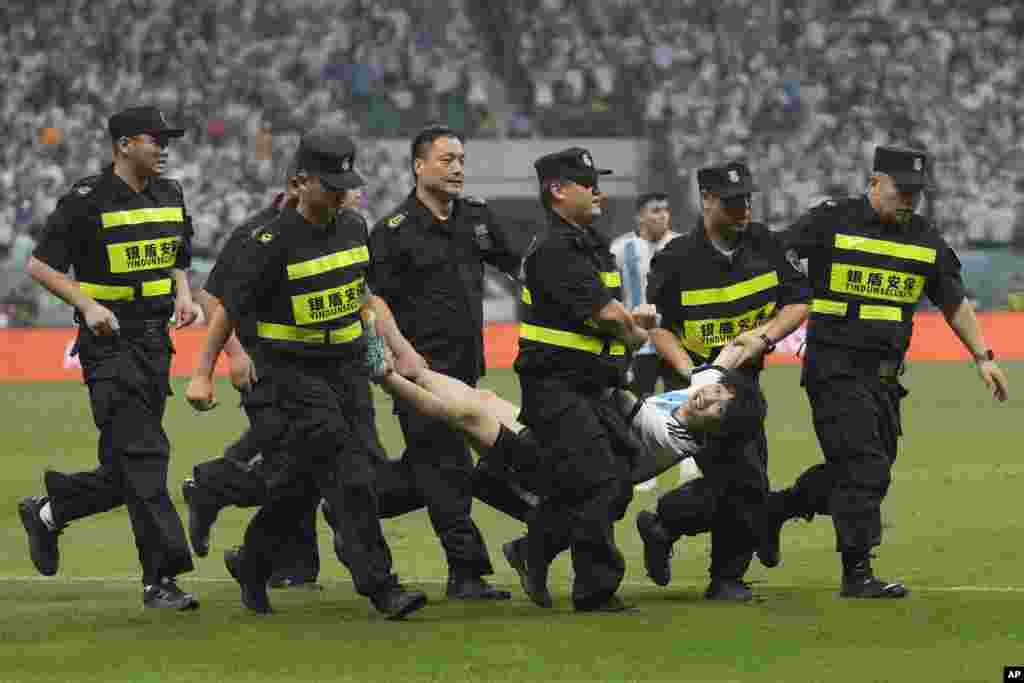 Security guards remove a pitch invader during the friendly soccer match between Argentina and Australia at Workers' Stadium in Beijing, China.
