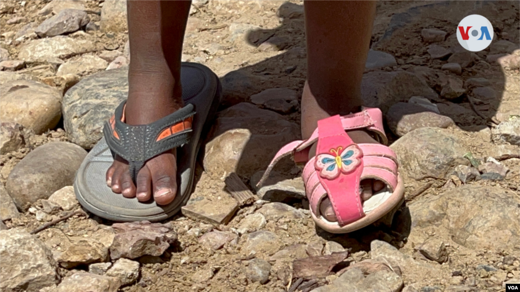 Una niña migrante haitiana, que vive en el Cañón del Alacrán, lleva puesta su sandalia en el pie izquierdo, y en el derecho una pantufla que no es de su talla. Foto: Celia Mendoza, 9 de abril de 2022. Tijuana México.