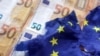 ARCHIVO - La ilustración muestra billetes de euros y una bandera rota de la Unión Europea.
