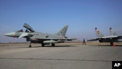 Vojni oficir prolazi između bugarskog MiG-29 i španskog aviona Eurofighter EF-2000 Typhoon II i MiG-29, u Graf Ignatievu, četvrtak, 17. februara 2022.