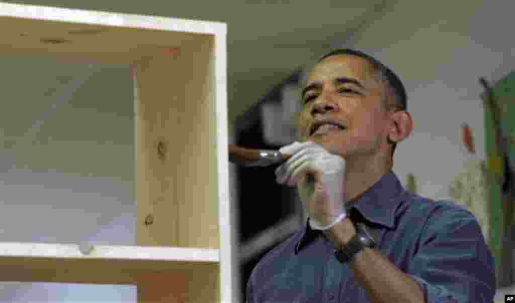 Tổng thống Barack Obama sơn một kệ sách tại Trường Tiểu học Burrville trong lúc gia đình Tổng thống tham gia một dự án phục vụ cộng đồng tại Washington, ngày 19/1/2013.