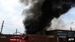 Los bomberos trabajan para controlar las llamas en el mercado central de Sloviansk, al este de Ucrania, el 5 de julio de 2022, luego de un presunto ataque con misiles por parte de las fuerzas rusas.