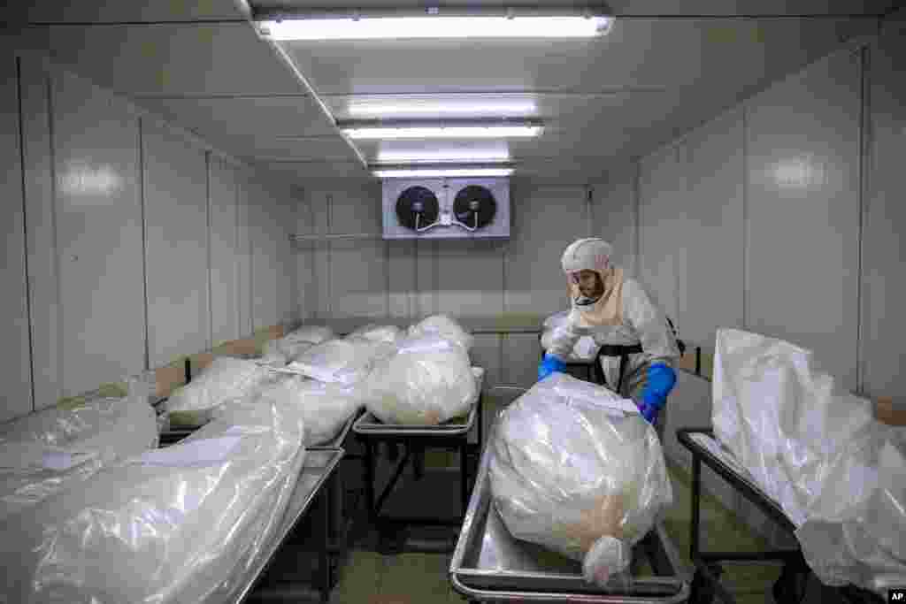 A worker from "Hevra Kadisha," Israel's official Jewish burial society, prepares bodies before a funeral procession at a special morgue for COVID-19 victims, in the central Israeli city of Holon, near Tel Aviv.