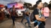 Decenas de migrantes que buscan llegar a Estados Unidos caminan por una carretera mientras salen de San Pedro Sula, Honduras, al amanecer del martes.