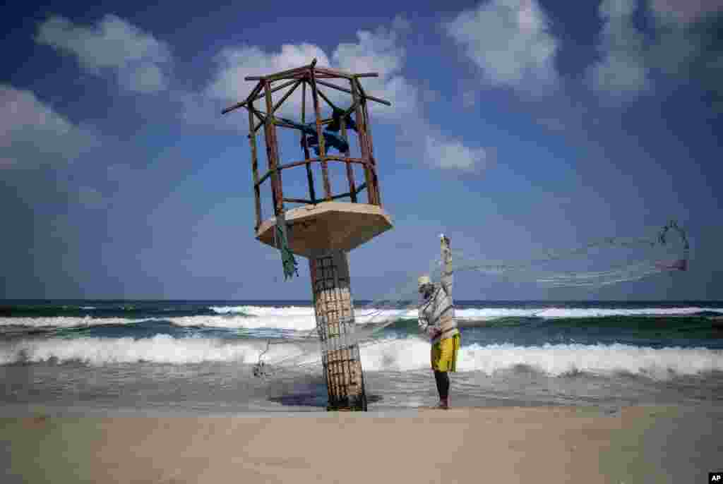 A Palestinian fisherman cleans up his fishing net after the Israeli decision to close Gaza&#39;s fishing zone, on the beach in Gaza City.