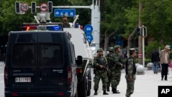 In this May 23, 2014 photo, armed Paramilitary policemen stand guard in Urumqi, China's northwestern region of Xinjiang.