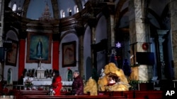 FILE - Chinese women walk past a decoration displaying a Baby Jesus doll part of a Nativity scene, at the Nantang Catholic Church in Beijing.