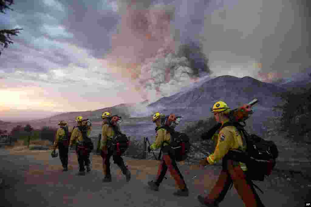 Firefighters walk in line during a wildfire in Yucaipa, California. Three fast-spreading wildfires sent people fleeing with one trapping campers at a reservoir in the Sierra National Forest, as a brutal heat wave pushed temperatures into triple digits in many parts of state.