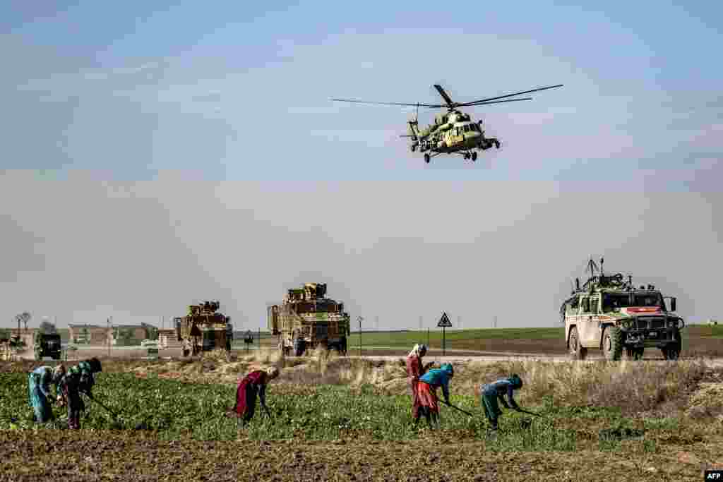 A Russian Mil Mi-17 military helicopter flies over a joint Russian-Turkish military patrol convoy in the countryside near Darbasiyah along the border with Turkey in Syria&#39;s northeastern Hasakah province.