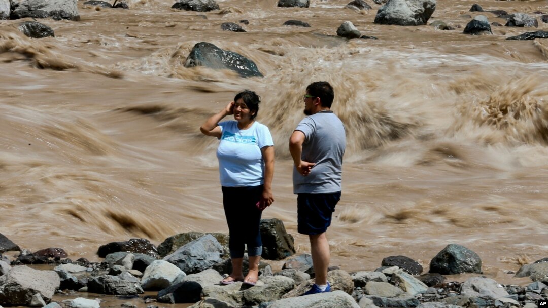 A couple looks at the overflowing Maipo River in San Alfonso, Santiago, Chile, Feb. 26, 2017. 