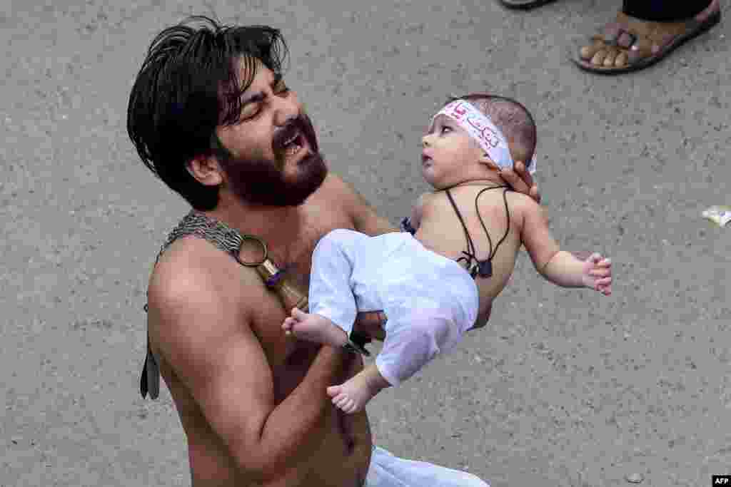 A Shi'ite Muslim holds his son before starting flagellating himself for an Ashura procession during the month of Muharram in Lahore, Pakistan.