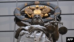 Cтатуя Фемиды, древнегреческой богини правосудия, и российский государственный герб у входа в Верховный суд России в Москве 
