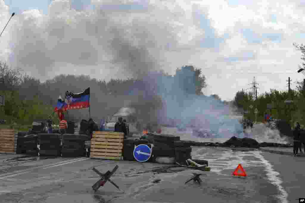 Smoke billows from burning tires at a pro-Russian checkpoint with a Donetsk republic flag following an attack by Ukrainian troops in Kramatorsk, Ukraine, May 3, 2014.