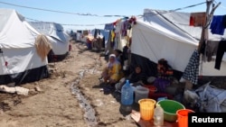 FILE - Displaced families, who fled from Islamic State violence in Mosul, sit at the Ali Awa refugee camp near Khanaqin city, Iraq, Oct. 22, 2014.