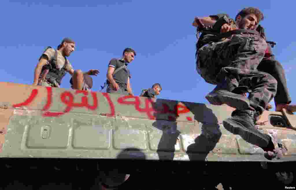 Một thành viên của Quân đội Giải phóng Syria nhảy ra từ một chiếc xe quân sự trong khu vực Saraqib gần Aleppo, ngày 12/10/2012.