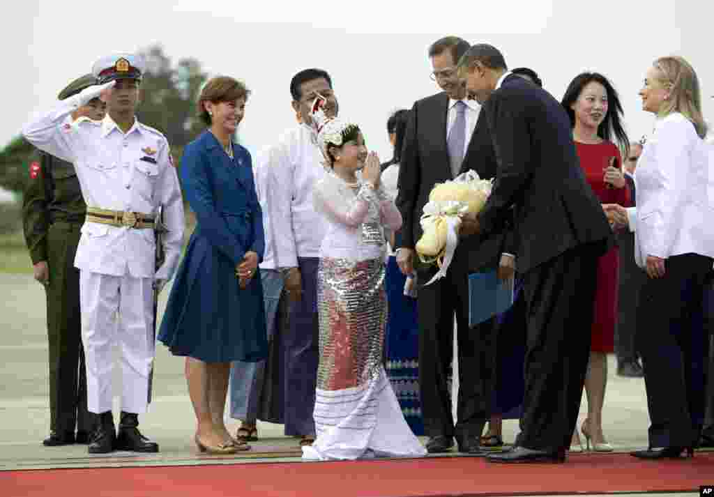 Một em thiếu nhi tặng hoa cho Tổng thống Mỹ Barack Obama khi ông cùng Ngoại trưởng Mỹ Hillary Clinton (phải) đặt chân xuống sân bay quốc tế Rangoon ở Miến Điện, ngày 19 tháng 11, 2012.