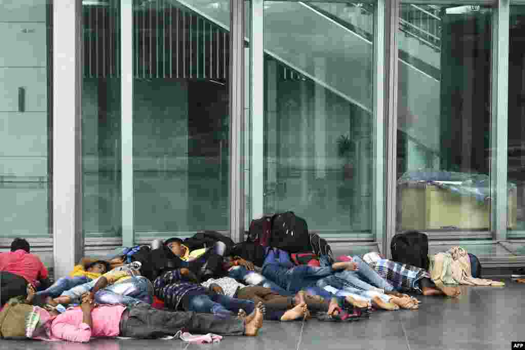 Migrant laborers rest outside the departure lounge of the Netaji Subhash Chandra Bose International Airport as their flights are cancelled during a day long state-imposed lockdown in Kolkata, India.