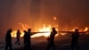 Firefighters, soldiers and local residents carry a hose as a wildfire burns in the town of Rafina, near Athens, Greece, July 23, 2018. 
