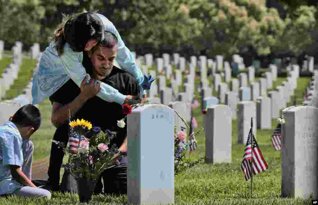Carla Martinez comforts her cousin Ceaser Martinez as he weeps over his brother&#39;s grave on Memorial Day at the Veterans National Cemetery in Los Angeles. Rodrigo Matinez was killed in action in Iraq in 2004.
