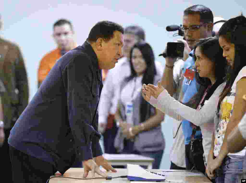 Ông Hugo Chavez nói chuyện với nhân viên bầu cử tại một trạm bỏ phiếu ở Caracas, ngày 7/10/2012.