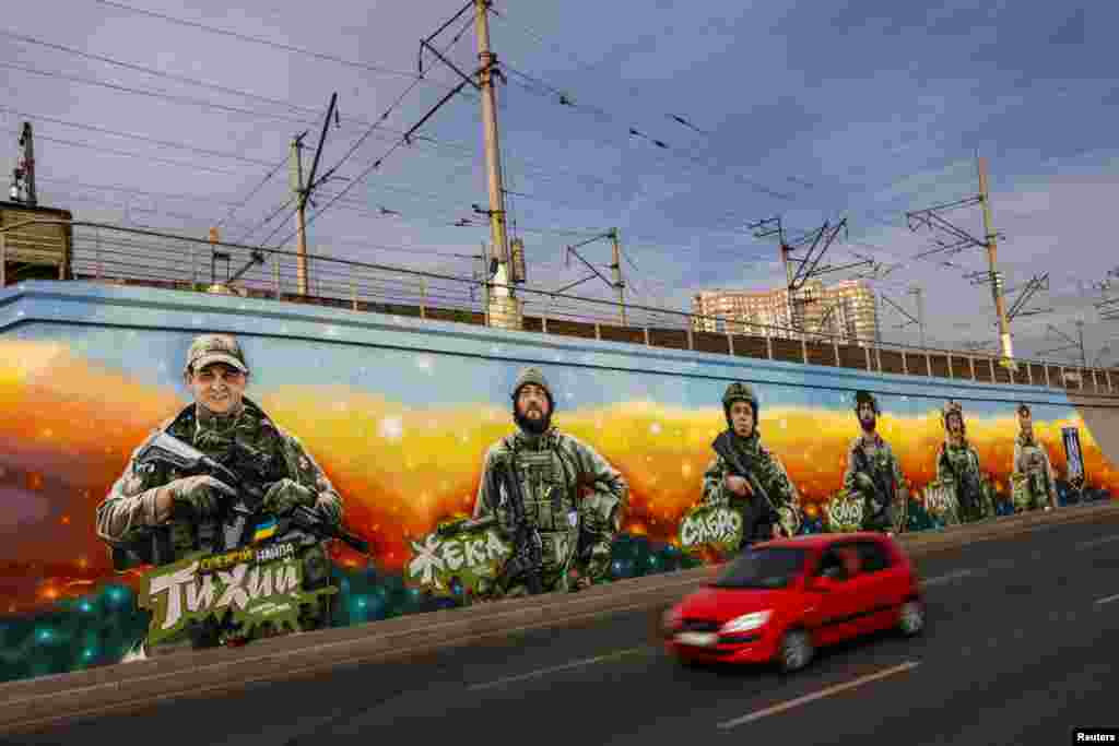 Un automóvil pasa junto a los murales de soldados ucranianos caídos de la unidad Gonor de los "Lobos Da Vinci" del Primer Batallón Separado que fue creado por el artista callejero ucraniano Eugene Gladenko, en medio del ataque de Rusia a Ucrania, en Kiev, Ucrania, el 4 de octubre de 2024. 