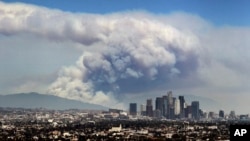 FILE - In this Monday, June 20, 2016 file photo, smoke from wildfires burning in Angeles National Forest fills the sky behind the Los Angeles skyline. Los Angeles County has the highest ranking in the National Risk Index. (AP Photo/Ringo H.W. Chiu)