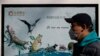 2020年3月11日，中国北京，一名戴着口罩的男子经过一张宣传保护野生动物的海报。