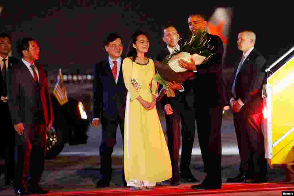 Tổng thống Obama nhận hoa khi bước xuống máy bay tại sân bay Nội Bài ở Hà Nội, tối ngày 22/5/2016. 