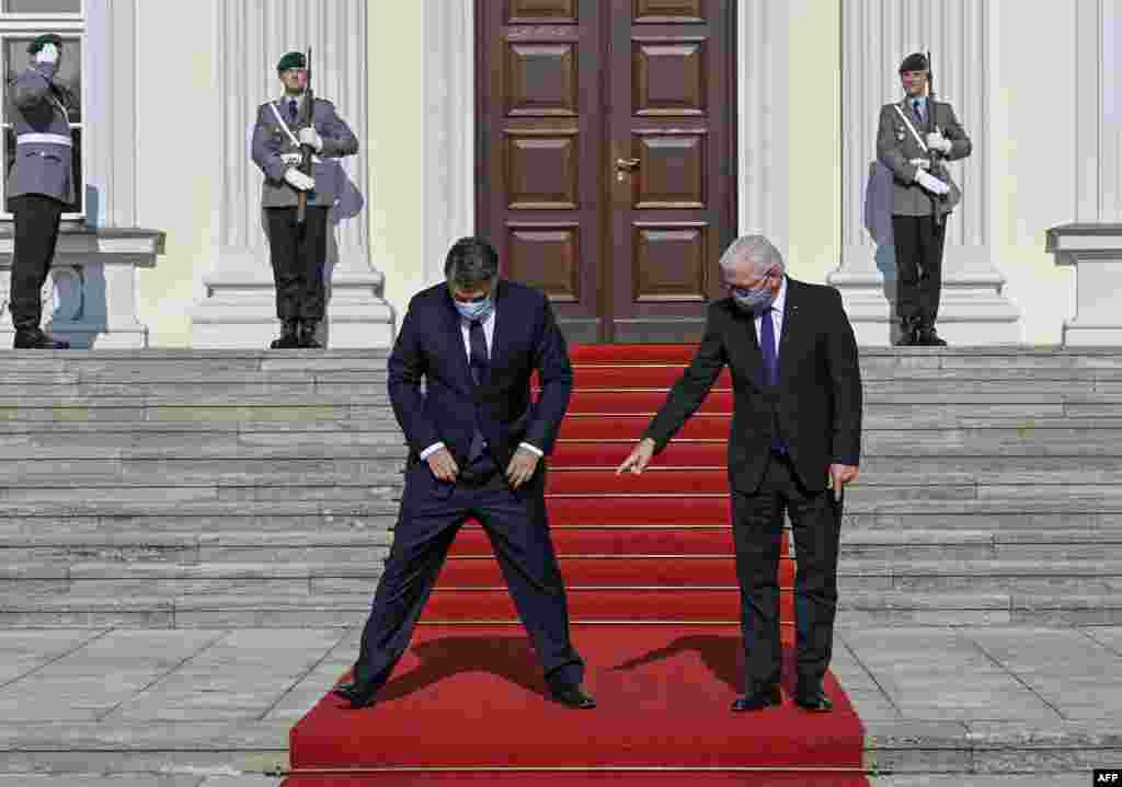Wearing face masks to protect agains the coronavirus, German President Frank-Walter Steinmeier, right, shows Croatia's President Zoran Milanovic where to stand during a welcome ceremony at the Bellevue Palace in Berlin, Germany.