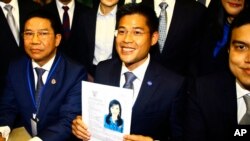 Leader of Thai Raksa Chart party Preecha Pholphongpanich, center, holds a picture of Princess Ubolratana at election commission of Thailand in Bangkok, Thailand, Friday, Feb. 8, 2019. (AP Photo)