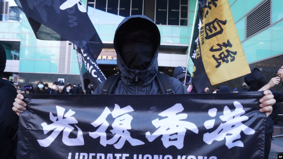 一位人在台灣的香港居民手舉“Liberate Hong Kong”橫幅在台灣街頭抗議中國當局扣留12名香港人。(美聯社照片）