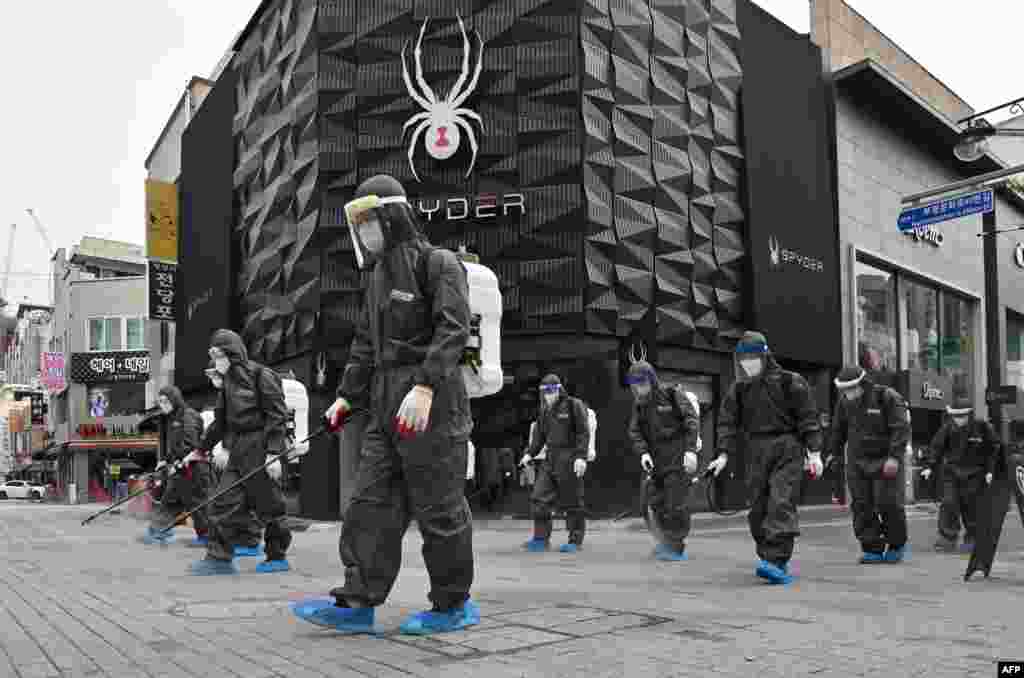 Health officials from Bupyeong-gu Office spray disinfectants at a shopping district in Incheon, South Korea, amid the COVID-19 pandemic.
