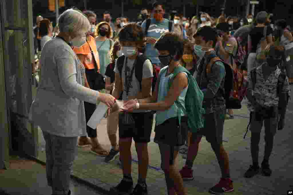 Students wearing face masks to prevent the spread of coronavirus disinfect their hands before entering their school in Barcelona, Spain.