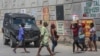 Los peatones pasan junto a un vehículo policial blindado en Puerto Príncipe, Haití, el viernes 4 de octubre de 2024.