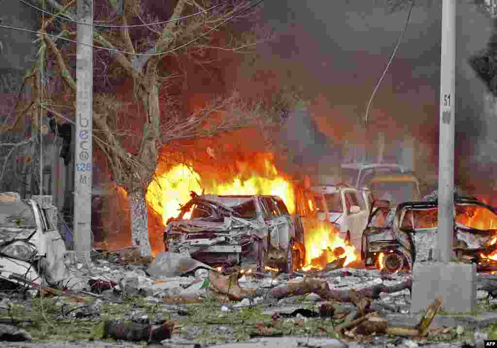Wrecked cars burn at the scene of a terror attack at the Ambassador Hotel, after a car bomb exploded, June 1, 2016, at a top Mogadishu hotel that houses several MPs, killing several people, and followed by a gun battle.