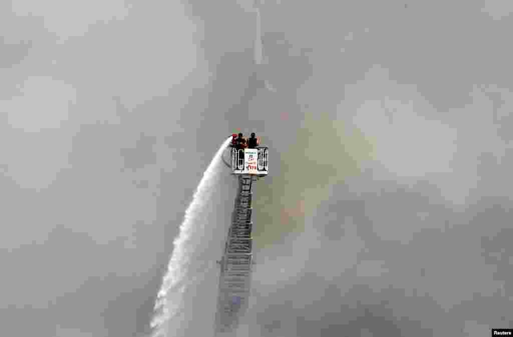 A man uses a water hose to put out the remains of a fire that broke out the day before at Beirut's port in Lebanon.