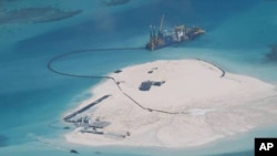 FILE - In this Feb. 25, 2014 file photo taken by surveillance planes and released May 15 by the Philippine Department of Foreign Affairs, a Chinese vessel, top center, is used to expand structures and land on the Johnson Reef, at the Spratly Islands in the South China Sea.