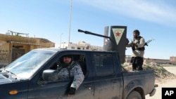 Islamic State militants ride in a Kurdish popular protection unit (YPG) vehicle captured during fighting in Tal Tamr, Hassakeh province, Syria.(AP Photo via militant social media account)