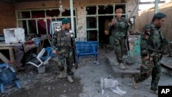Afghan security forces look at the damage from clashes between Taliban fighters and Afghan forces in Kandahar Airfield, Afghanistan, Wednesday, Dec. 9, 2015.