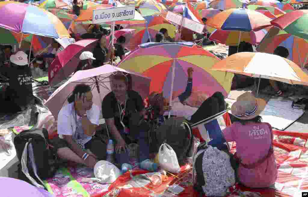 Anti-government protesters sit under beach umbrellas during a rally at the Democracy Monument, Bangkok, Thailand, Jan. 12, 2014. 
