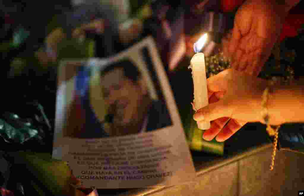 Một phụ nữ đặt một cây nến trước bức ảnh của Tổng thống Hugo Chavez bên ngoài Đại sứ quán Venezuela ở La Paz, Bolivia, ngày 5/3/2013.