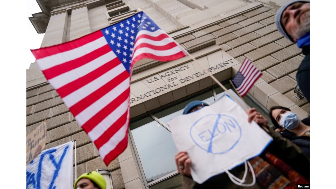 Moun kenbe pannkat devan bilding USAID a apre milyade Elon Musk lanse yon jefo pou redui anplwaye ajans la epi femen l nan Washington, 3 Fevriye 2025.