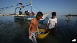 Ngư dân Philippines đưa cá đánh bắt được vào bờ. Các ngư dân nói tàu hải giám của Trung Quốc xua đuổi họ ra khỏi vùng biển tranh chấp không cho họ vào đánh bắt cá trong vùng biển từng là nơi mang lại nguồn cá phong phú từ mấy chục năm nay