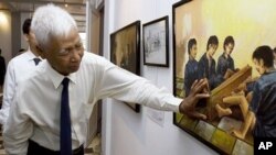 Ông Vann Nath, 1 trong 7 người sống sót ở nhà tù Tuol Sleng, giải thích một bức tranh nói về cách tra tấn trong tù, tại buổi trưng bày tranh của ông ở Phnom Penh