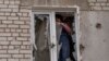 ARCHIVO - Una mujer coloca plástico sobre su ventana dañada después de un ataque ruso la noche anterior, en la zona residencial de Mikolaiv, Ucrania, el 29 de marzo de 2022. AP