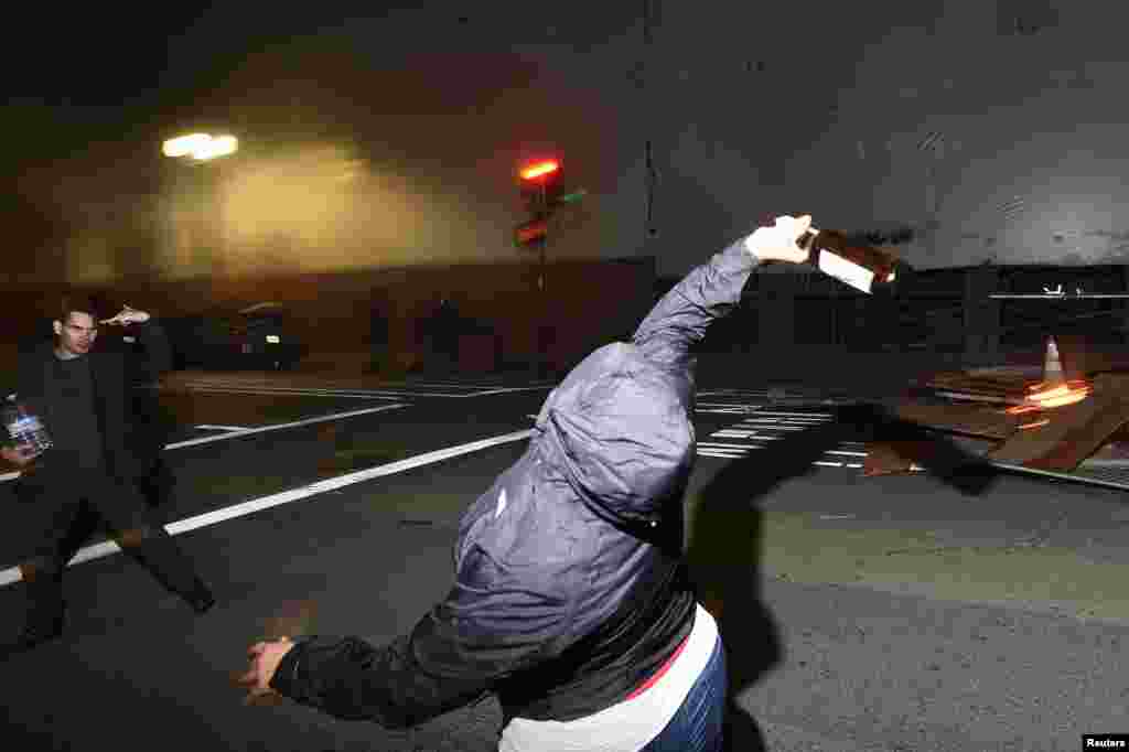 A protester throws a bottle at police officers following the election of Republican Donald Trump as President of the United States in Oakland, California, U.S., Nov. 9, 2016.