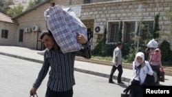 Người tị nạn Syria khiêng đồ đạc vượt biên giới sang Libăng lánh nạn